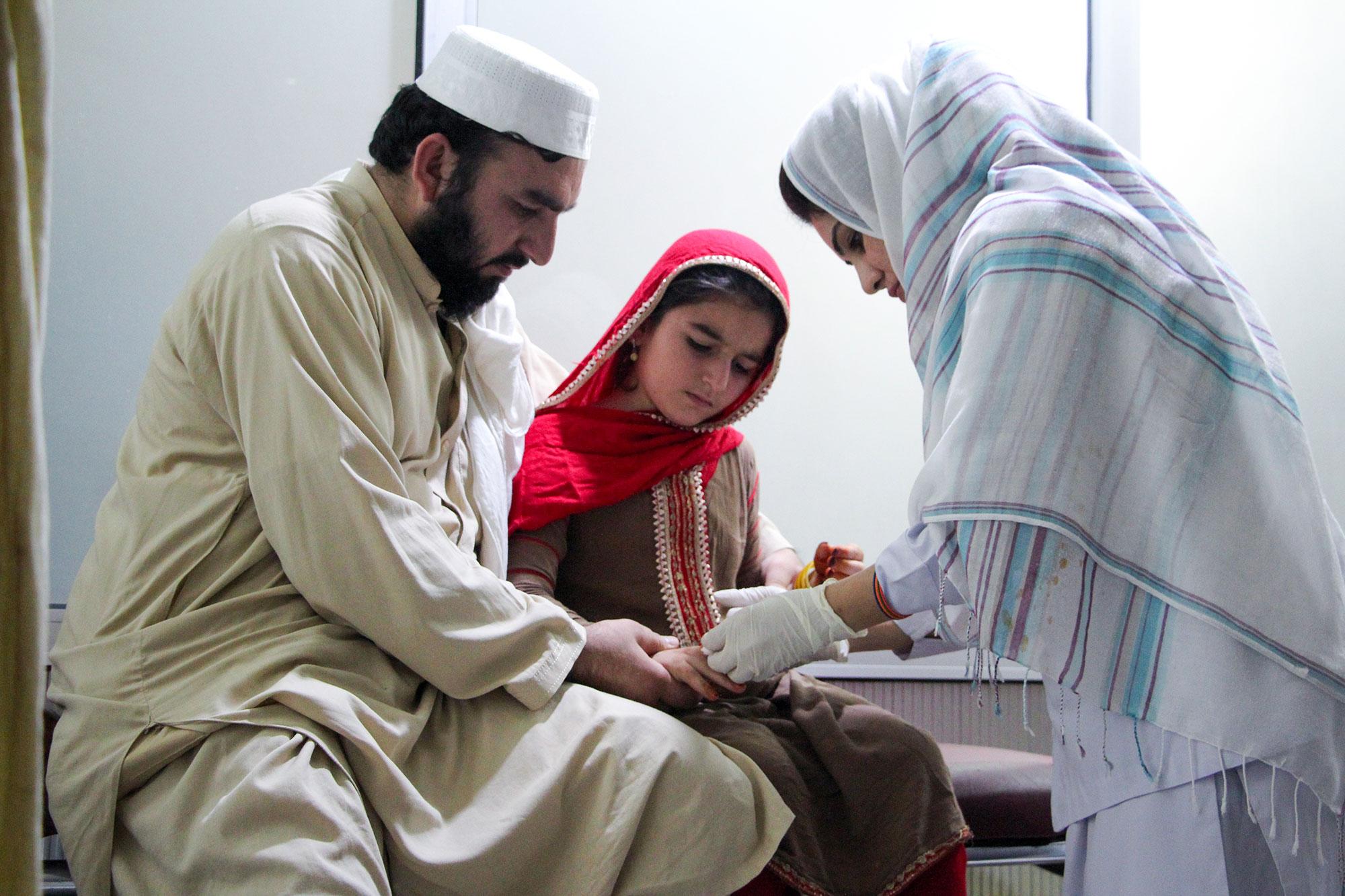 Subhan tranquiliza a su hija Afia mientras le ponen una inyección para la leishmaniasis cutánea, en el centro de tratamiento especializado de MSF en el Hospital Nasirula Khan Babar, en Peshawar. Pakistán.
